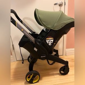 Green Doona. Good Condition. Rain Cover Included. NO CAR BASE!!!!!